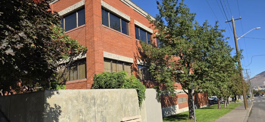 The corner elevation of the detachment building with a public bench and sidewalk.